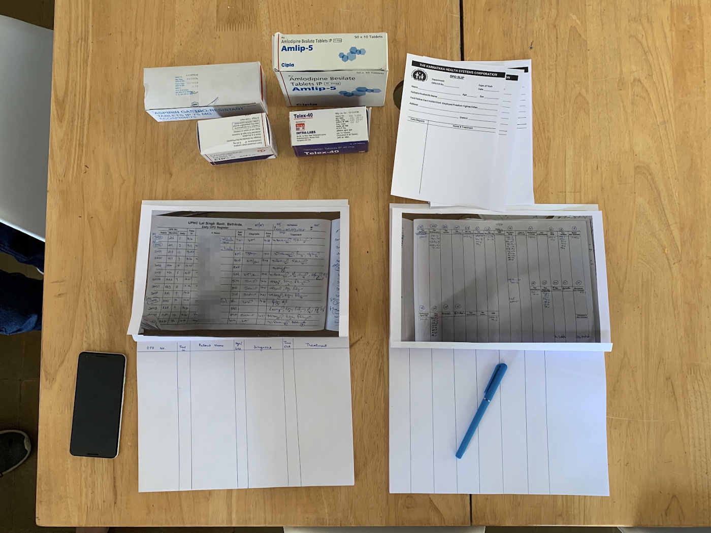 Outpatient registration counter and pharmacy with paper registers, medications and prescription slips.